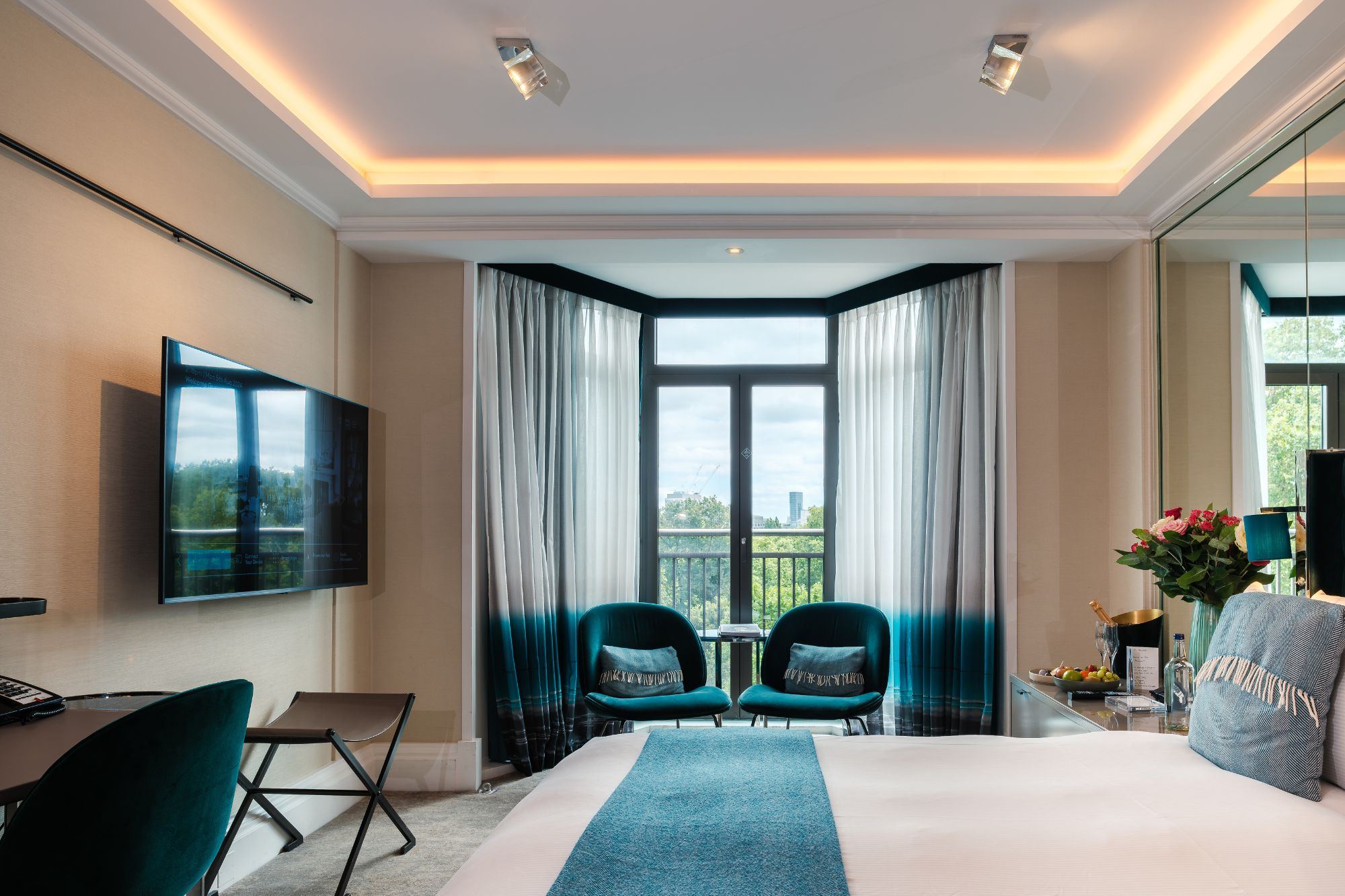 A Green Park View room with a deep blue headboard and warm lamplight